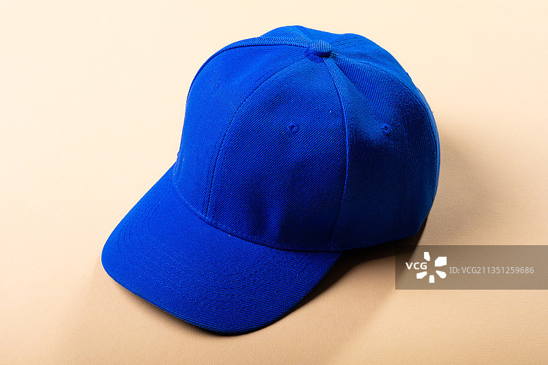传统的尖顶蓝色棒球帽在浅棕色背景上的构图图片素材