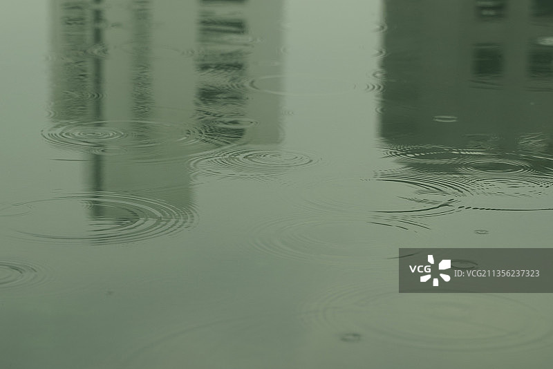 一滴雨水落在绿色的地板上。反映城市景观。图片素材