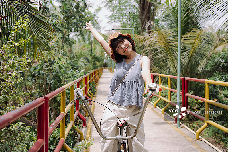 年轻的亚洲泰国妇女旅行者骑自行车在乡村边桥。当地的旅行。图片素材