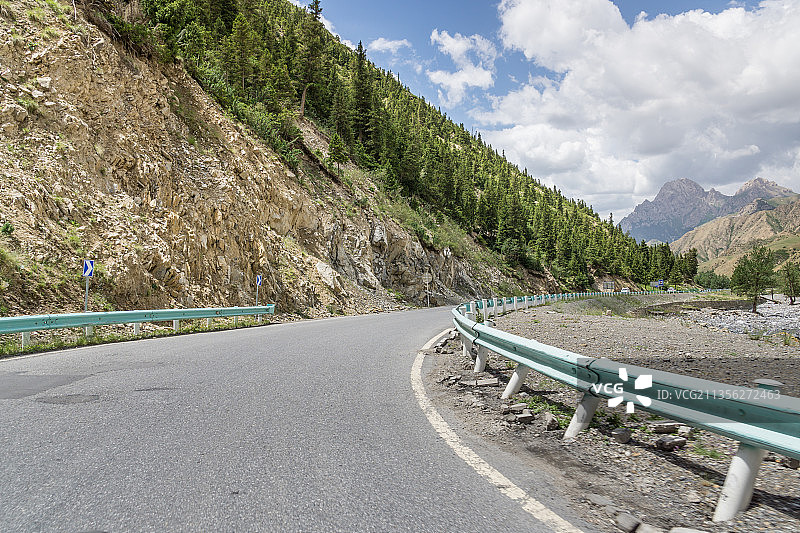 夏季中国新疆中高山森林背景前的公路弯道图片素材