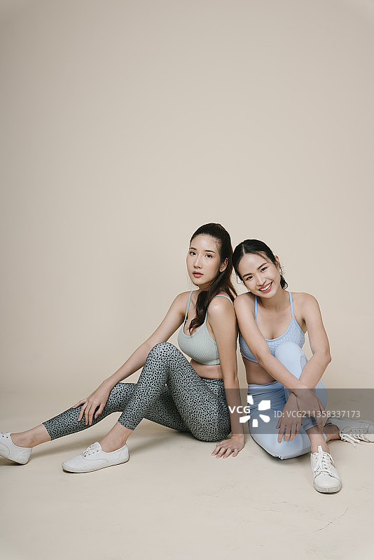 两个运动员的肖像亚洲运动妇女坐在一起在工作室的灯光。图片素材
