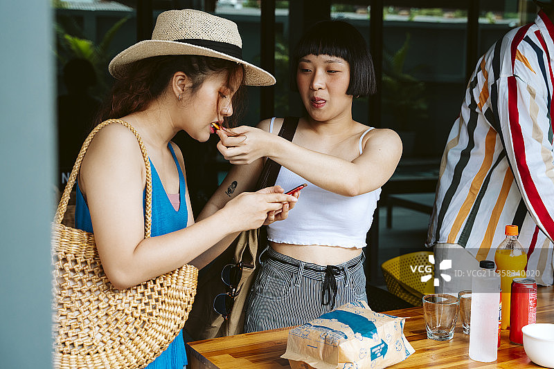两个年轻的女游客在夏季派对上吃零食。图片素材