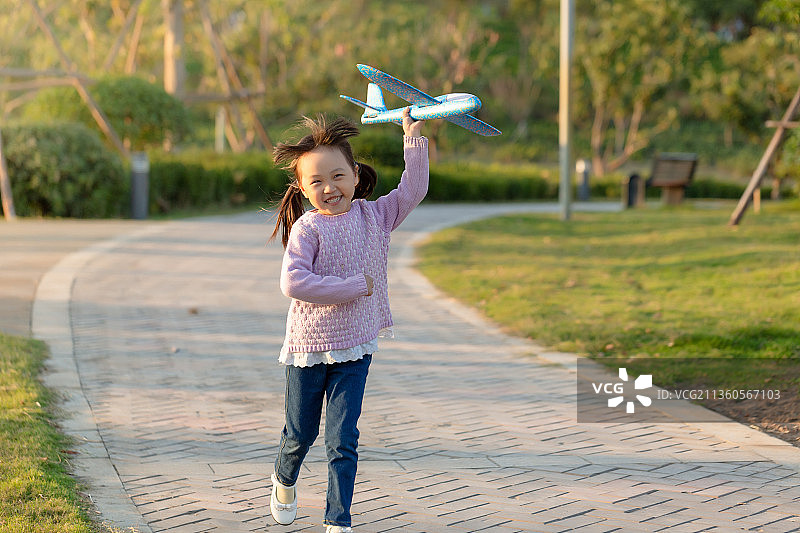 拿着飞机玩具在公园里奔跑的孩子图片素材