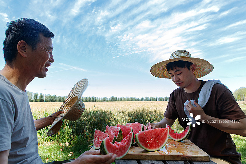 农民在田地旁休息吃西瓜图片素材
