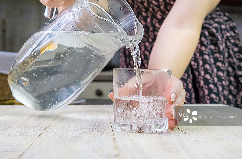 女孩把水倒进一个杯子里选择性地聚焦图片素材