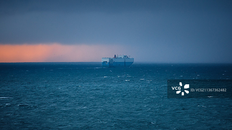 海上天际线行驶于夕阳与暴风雨间的轮船图片素材