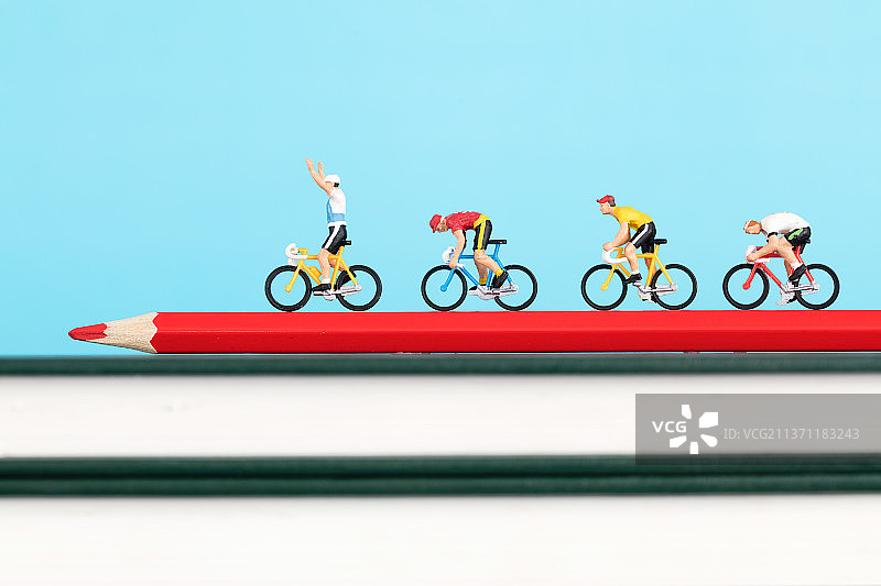 一群骑赛车的微缩模型行驶在彩铅笔上铅笔在书上图片素材