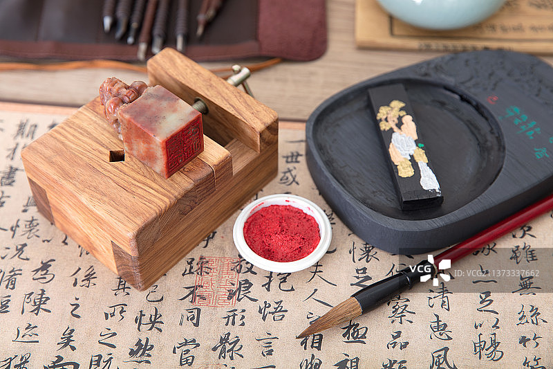 中国书法作品背景上的刻床和刻好的印章及砚台和印泥图片素材