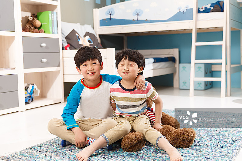 两个男孩坐在卧室的地毯上图片素材