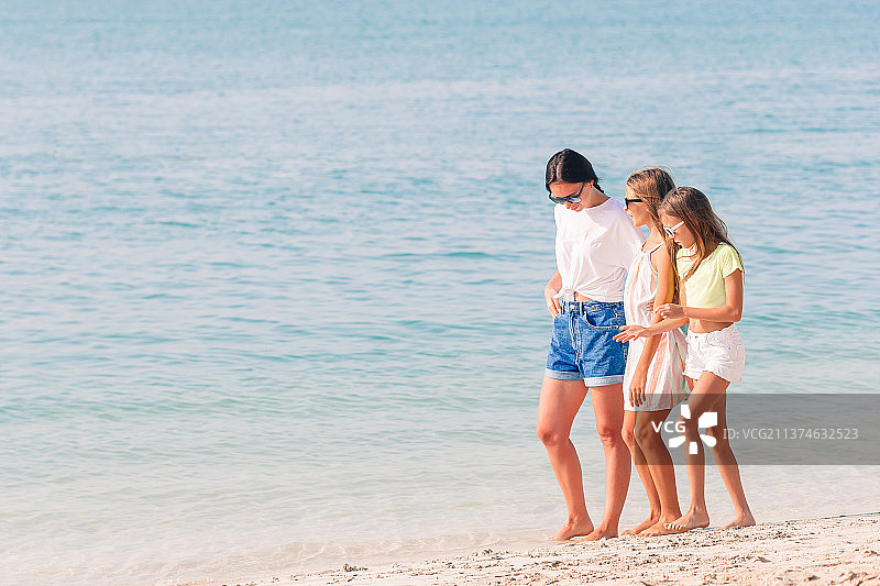 可爱的小女孩和年轻的妈妈在热带白沙滩上图片素材
