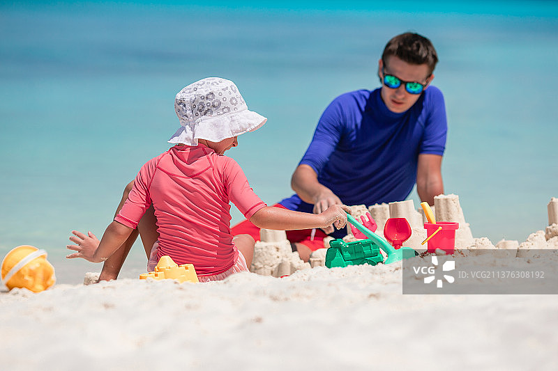 爸爸和孩子在热带海滩堆沙堡一家人在玩耍图片素材