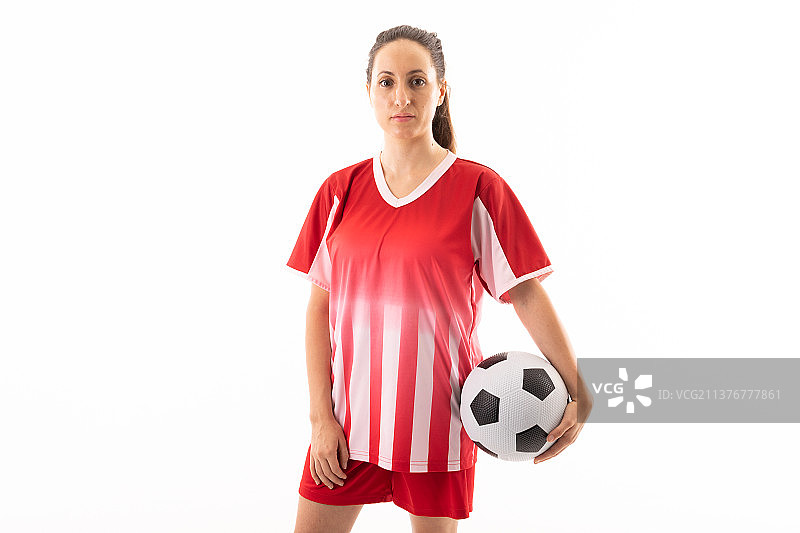 白人年轻女足球运动员与球站在白人背景的肖像图片素材