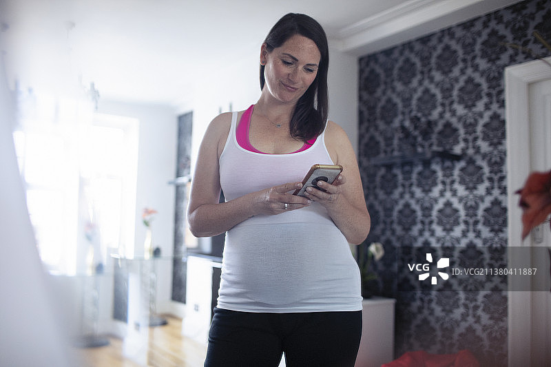穿着背心用智能手机的孕妇图片素材