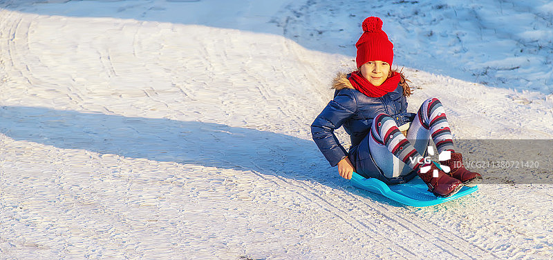 一个小女孩在雪中滑下山坡选择性聚焦图片素材