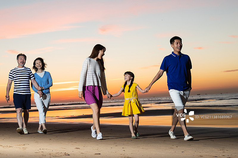夕阳下在海边散步的幸福家庭图片素材
