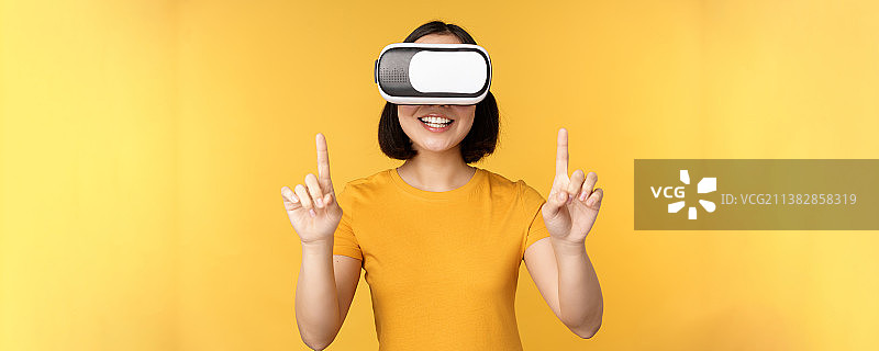 年轻的亚洲女性玩虚拟现实，使用虚拟现实眼镜图片素材