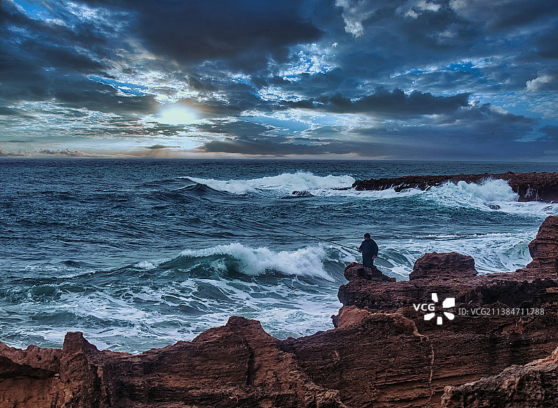 愤怒的大海，男子坐在海滩岩石上对着天空，拉塔基亚，叙利亚图片素材