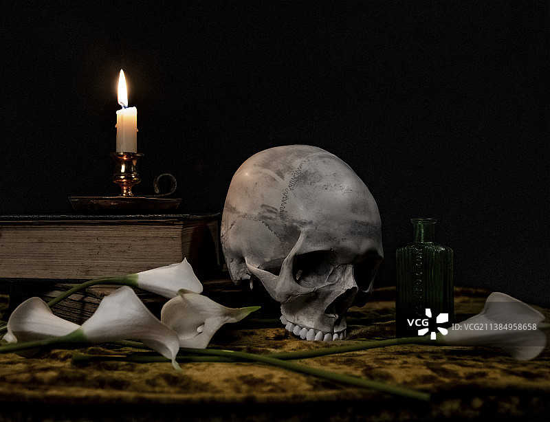 书中的头骨，被照亮的蜡烛和桌子上的头骨的特写，霍尔舍姆，英国，英国图片素材