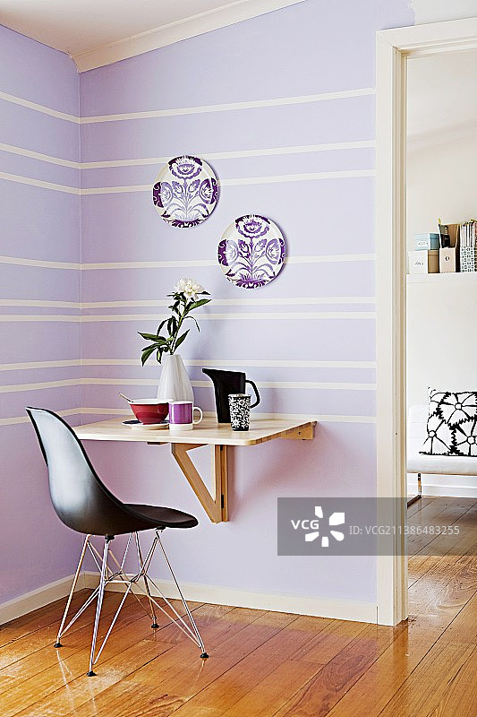小小的紫色用餐区配有简单的折叠桌和黑色设计师椅图片素材