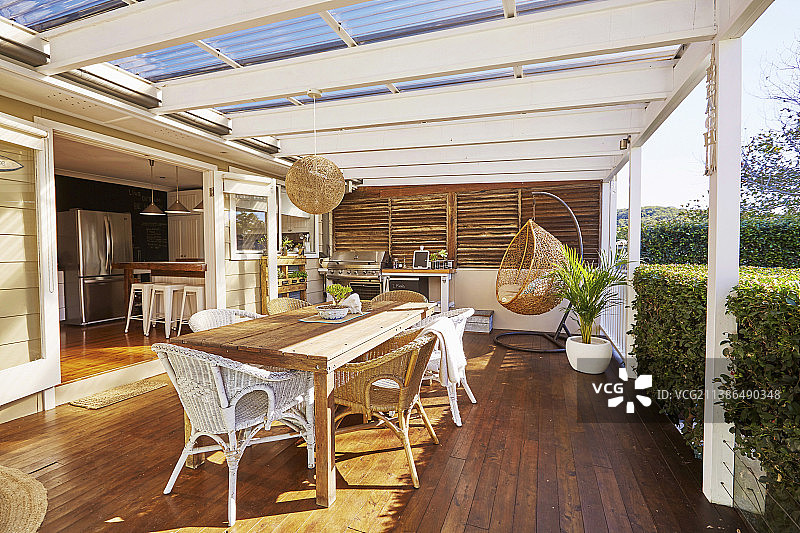 木制露台，配有餐桌，柳条家具和户外厨房图片素材