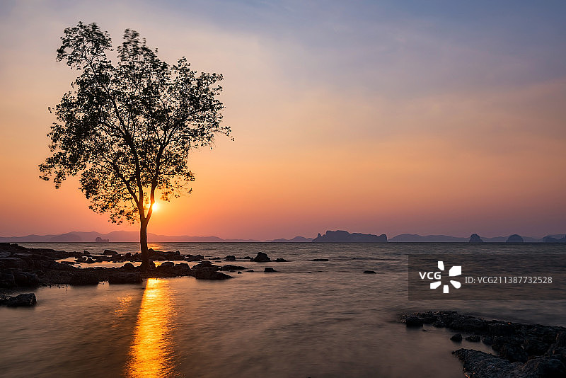 树和岩石与运动波在海滩日落，甲米，泰国图片素材