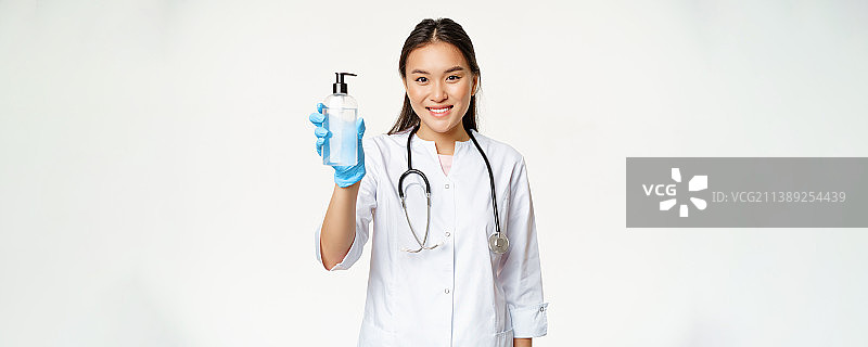 微笑的亚洲医生展示洗手液，一瓶防腐剂图片素材