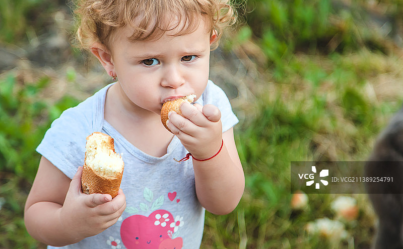 一个孩子在公园里吃面包选择性聚焦图片素材
