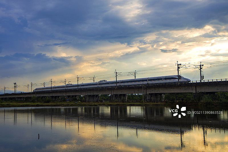 晚霞中水边高架桥上行驶的高速列车图片素材