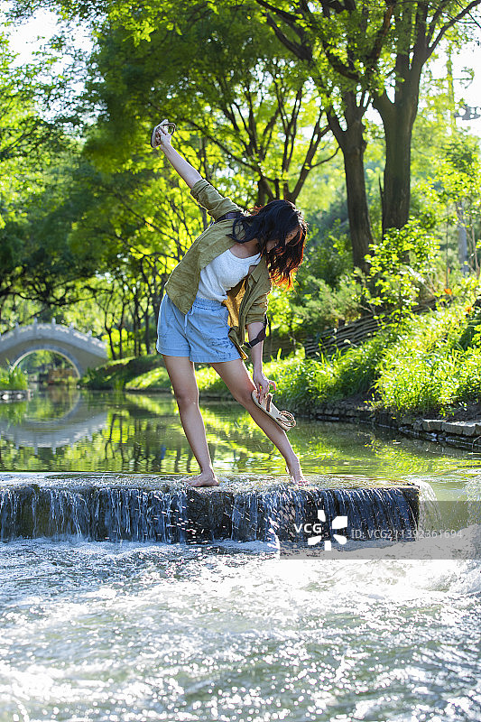 年轻女孩在公园小河里跳舞，享受大自然图片素材