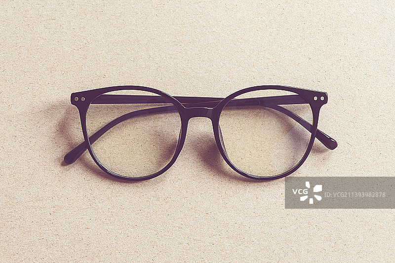 眼镜在米色硬纸板的背景，极简的平面铺设图片素材