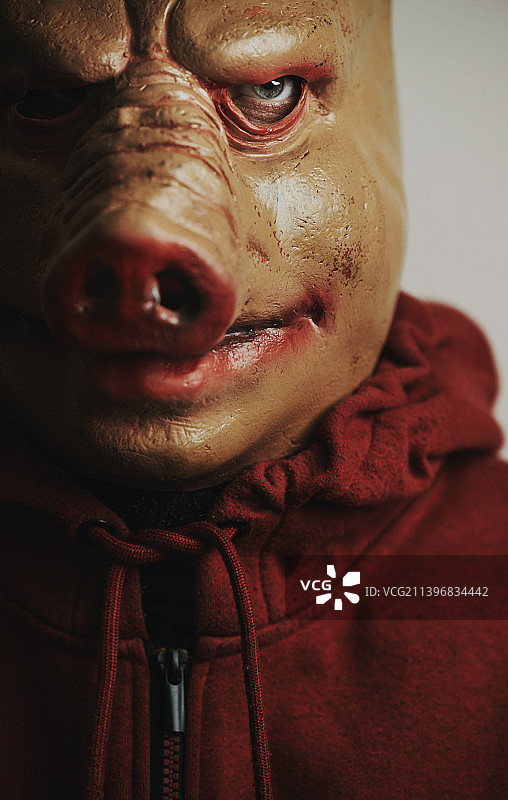 万圣节-男人在可怕和令人毛骨悚然的猪面具靠墙图片素材
