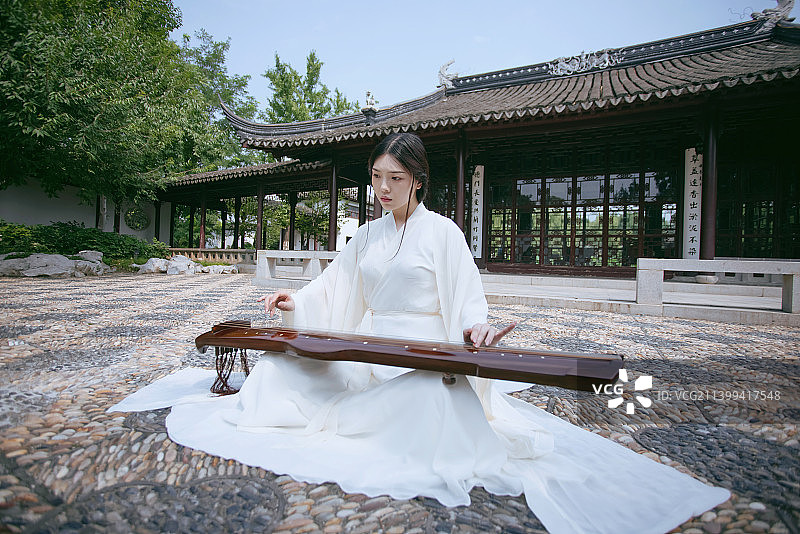 一个汉服美女坐在中式大殿前弹古琴图片素材
