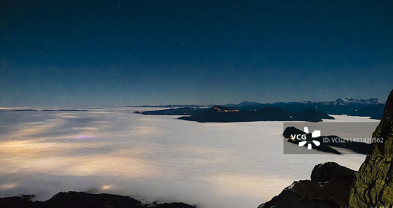 从山上到山谷的夜景，下面的云海照亮了城市图片素材