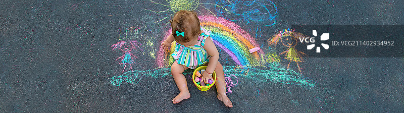 宝宝用粉笔在人行道上画了一道彩虹选择性聚焦图片素材
