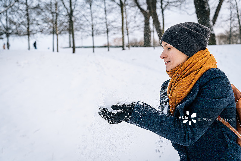 一个穿着暖和衣服的女人用手扔雪图片素材