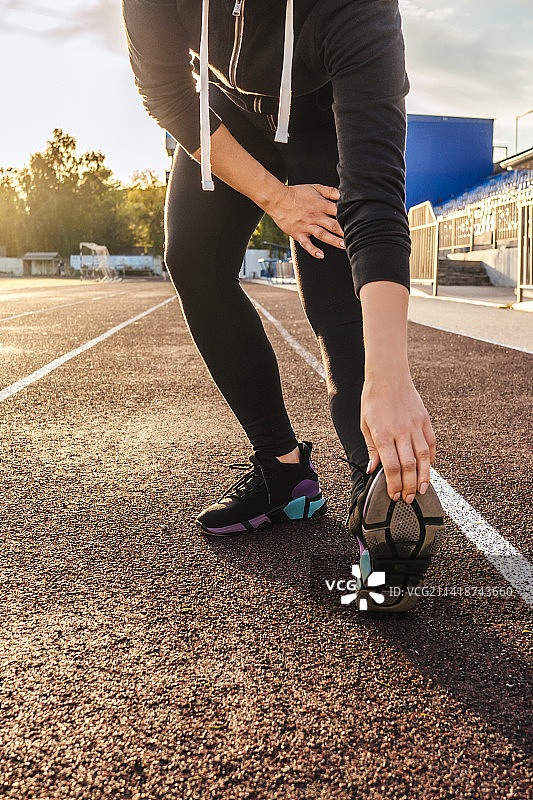 俄罗斯，一名女子在体育场跑步前伸展身体图片素材