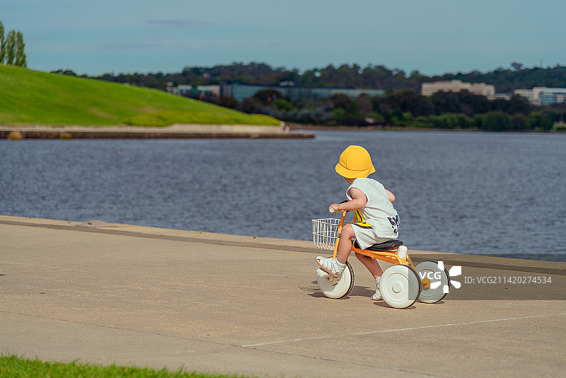 植物园湖畔骑三轮童车的小男孩图片素材
