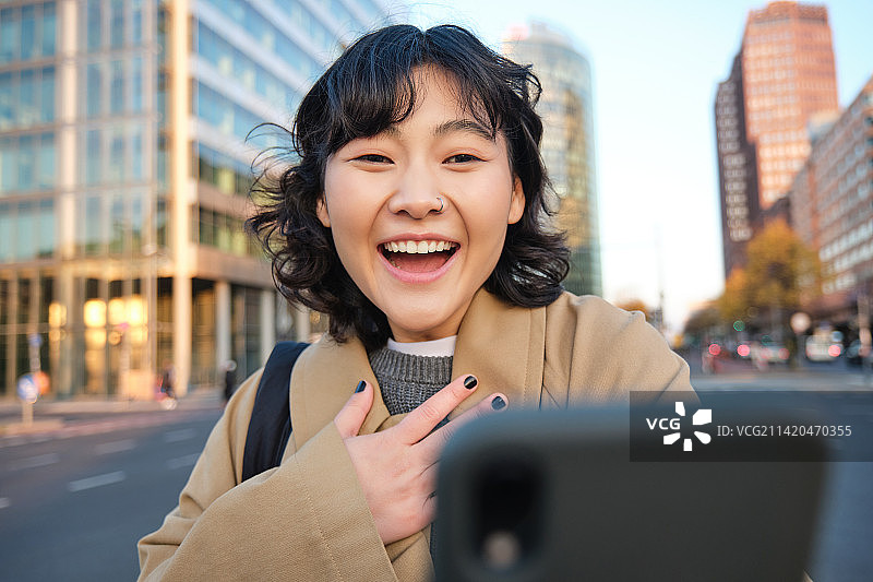 韩国女孩用智能手机视频聊天的图片，看着她的手机图片素材