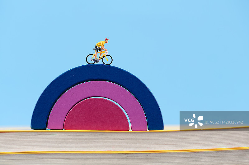 微缩创意骑车行驶在彩虹桥上图片素材