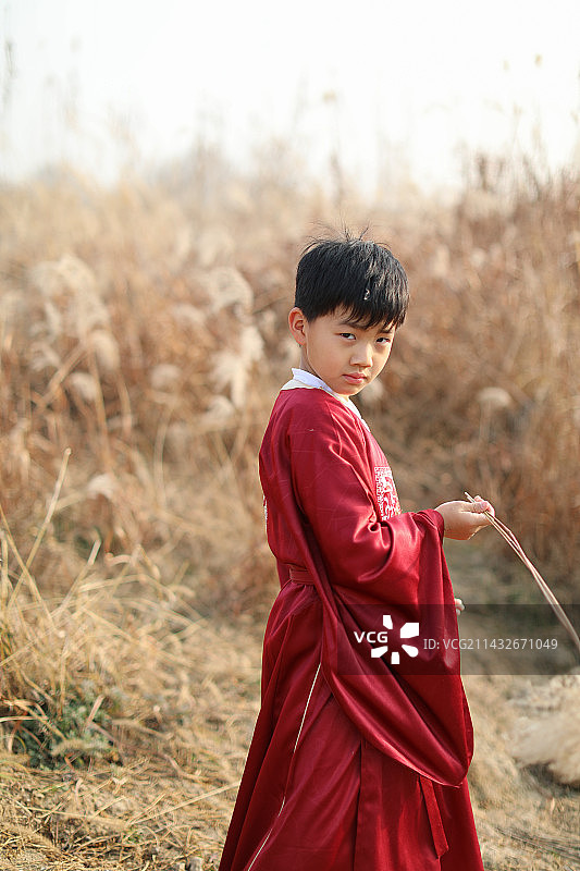 可爱的男孩站在草地上拿着芦苇图片素材