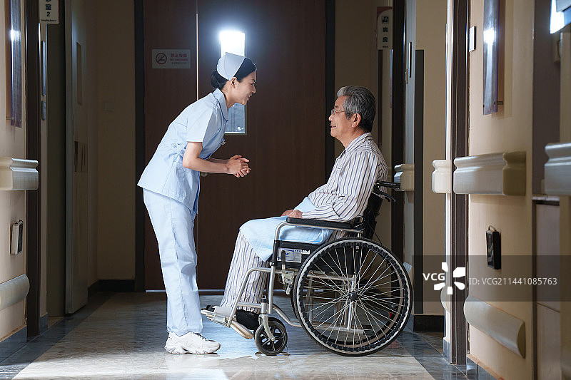 走廊内护士照顾坐轮椅的老人图片素材