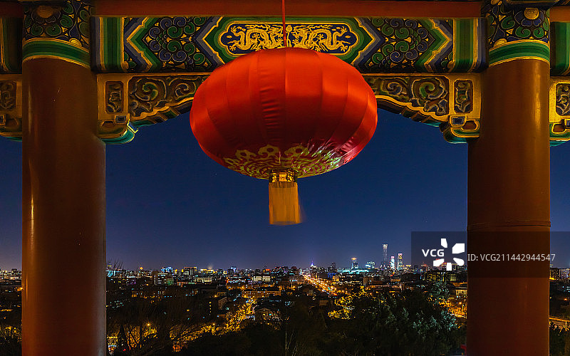 春节里，天气晴朗的夜晚，从北京景山公园万春亭里红灯笼下，远眺国贸CBD摩天大楼楼群的夜景灯光。图片素材