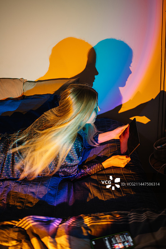 西班牙，一名年轻女子坐在家里的床上看书图片素材