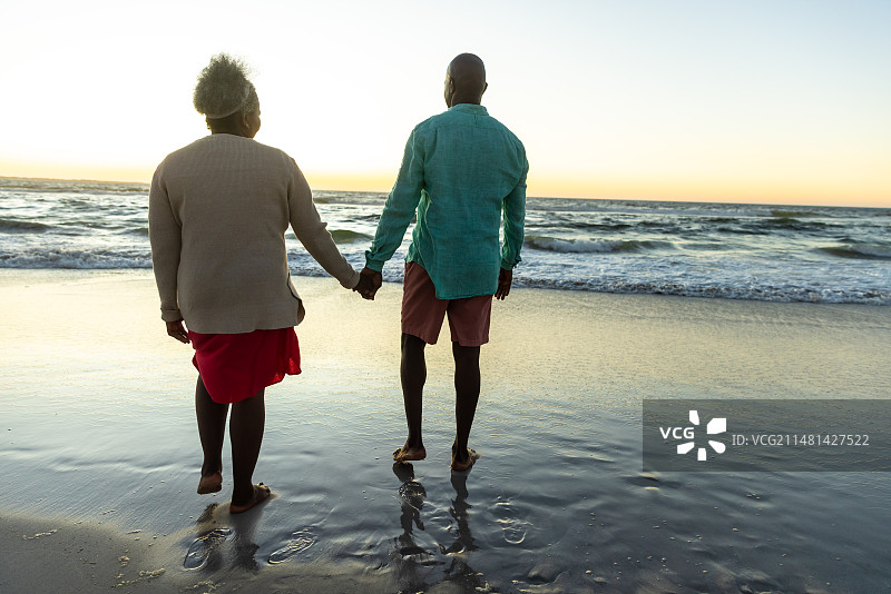 一对年长的非裔美国夫妇在日落时享受宁静的海滩，还有复制空间图片素材