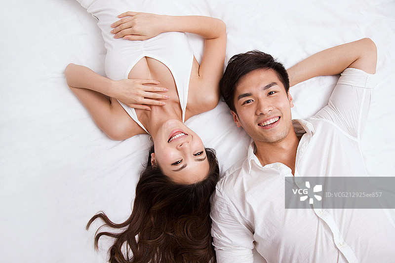 东方年轻夫妇躺在床上图片素材