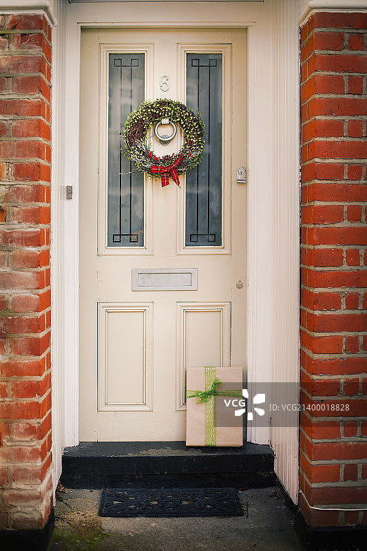 圣诞装饰品。在一所房子的前门上有一个红色蝴蝶结的圣诞花环。图片素材