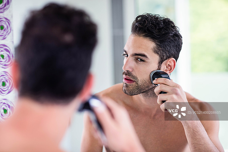 英俊的男人对着镜子刮胡子图片素材