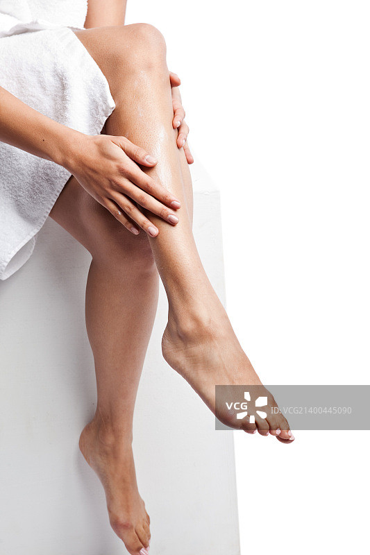一个美丽的黑人妇女在她的腿上涂乳液的孤立镜头图片素材
