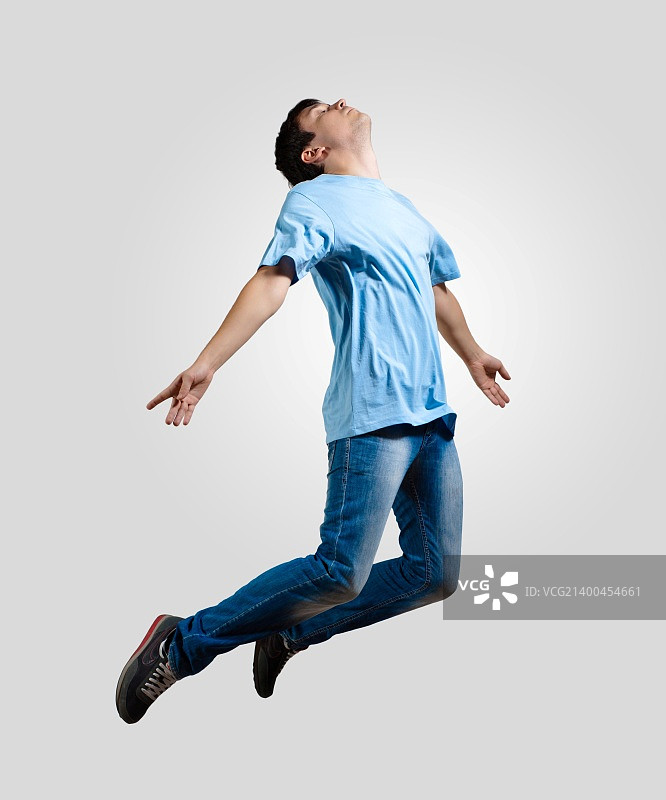 现代苗条的嘻哈风格的人跳跃跳舞在一个灰色的背景图片素材