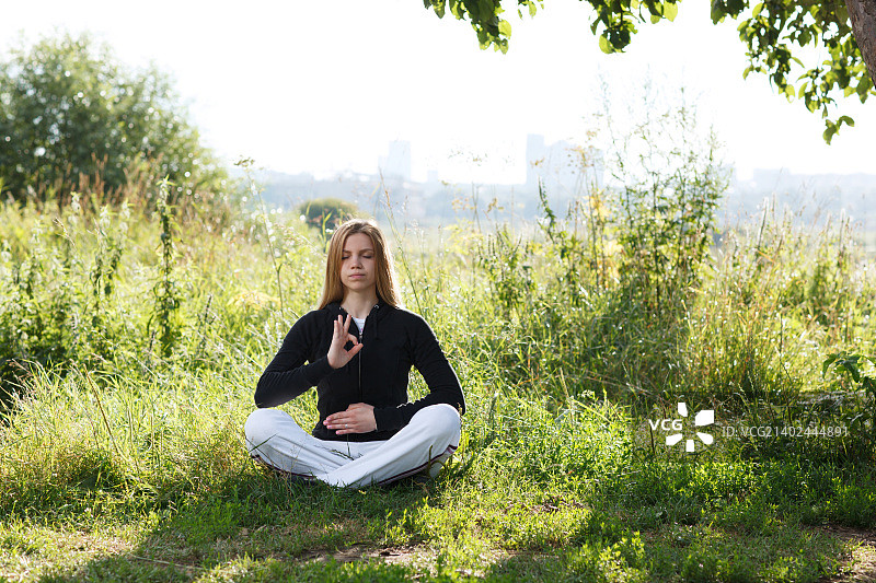 一个年轻女子在城市公园里练瑜伽图片素材